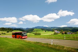 Ein roter Südbadenbus fährt durch eine sonnige Schwarzwaldlandschaft